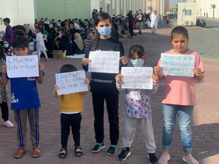 Afghan children hold banners during a protest over lenghty U.S. relocation process, at a Gulf facility where they have been housed since fleeing their homeland last year, in Abu Dhabi, United Arab Emirates, February 10, 2022 in this picture obtained from
