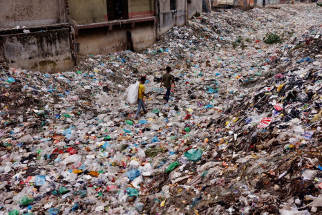 Children walk over a polluted area as they collect plastic materials in Dhaka, Bangladesh, January 24, 2022. 
