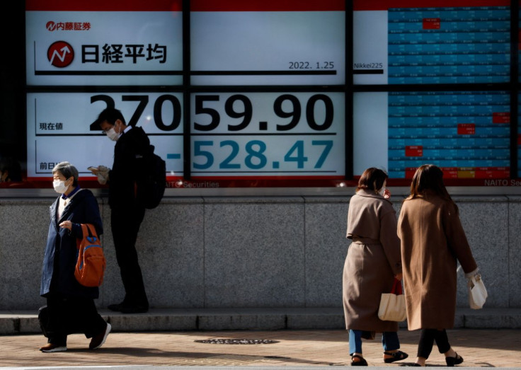 Passersby wearing protective face masks walk past a stock quotation board, amid the coronavirus disease (COVID-19) pandemic, in Tokyo, Japan January 25, 2022.  