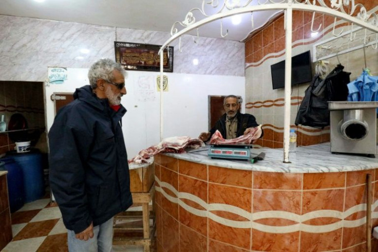 A butcher weighs meat for a customer at his shop in Shahat, Libya, where rising prices make daily life a challenge
