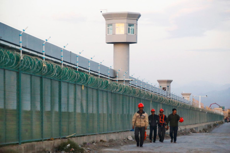 Workers walk by the perimeter fence of what is officially known as a vocational skills education centre in Dabancheng in Xinjiang Uighur Autonomous Region, China September 4, 2018.