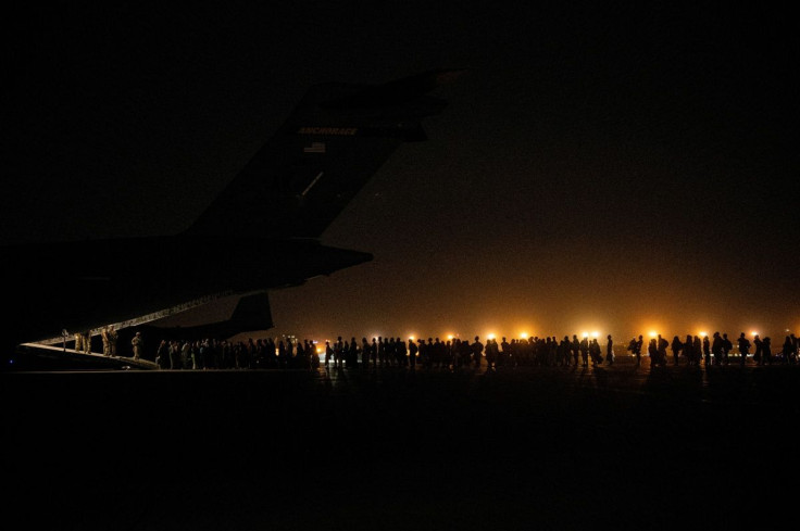 Evacuees from Afghanistan board a military aircraft during an evacuation from Kabul, in this photo taken on August 19, 2021 at undisclosed location and released on August 20, 2021. Staff Sgt. Brandon Cribelar/U.S. Marine Corps/Handout via REUTERS THIS I