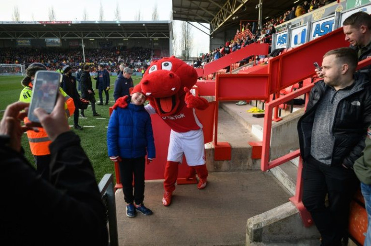 A supporter poses for photographs with Wrex the Dragon, the official team mascot of Wrexham