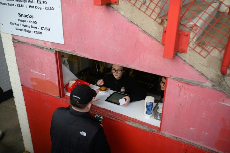 A supporter buys a pie from a food hatch at Wrexham's Racecourse Ground