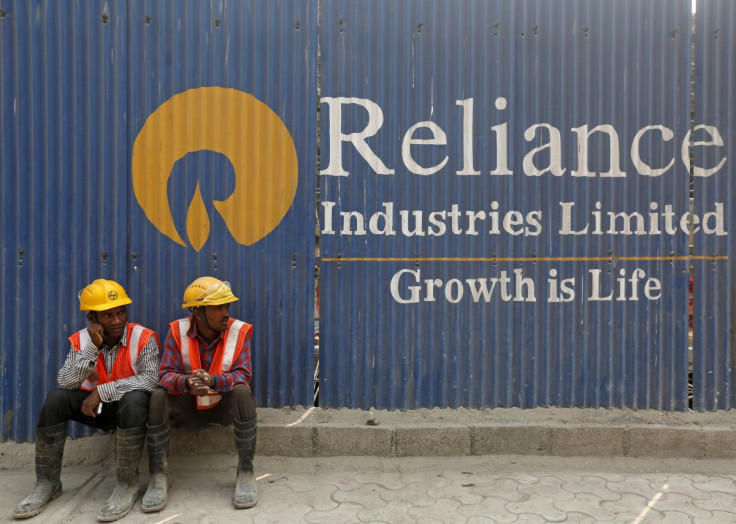 Labourers rest in front of an advertisement of Reliance Industries Limited at a construction site in Mumbai, India, March 2, 2016.