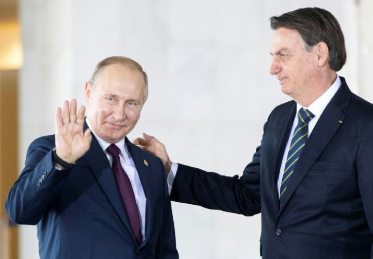 In this file photo taken on November 14, 2019 Russia's President Vladimir Putin (L) waves next to Brazil's President Jair Bolsonaro (R) before the 11th BRICS Summit at the Itamaraty palace in Brasilia