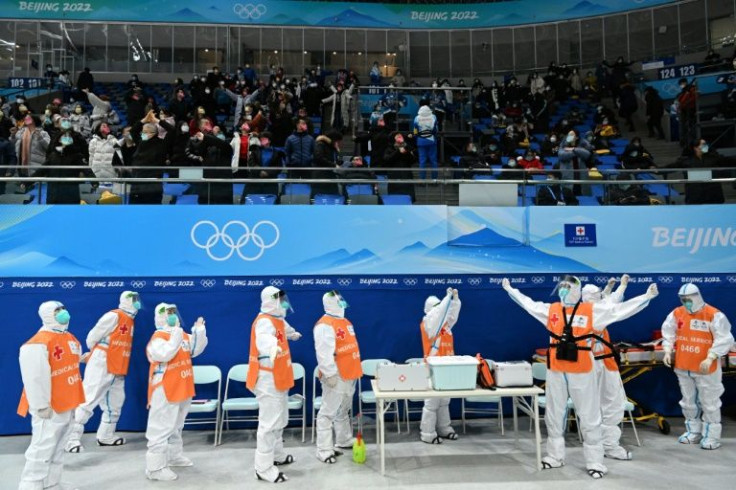 Members of a medical team wearing personal protective equipment stretch during an ice hockey match