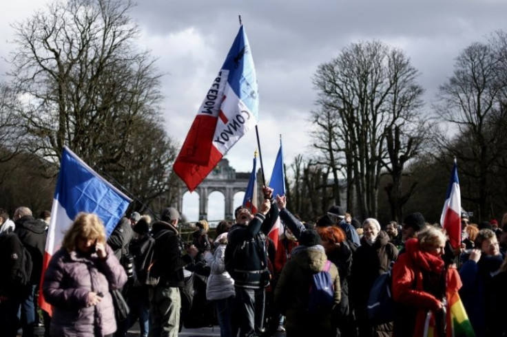 People wave French flags as they gather for an unauthorized demonstration in the center of Brussels, as part of a Canada-style protest convoy against Covid-19 regulations on February 14, 2022