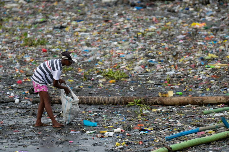 A woman picks up plastic cups along the riverbank of Pasig river, in Manila, Philippines, June 10, 2021. 