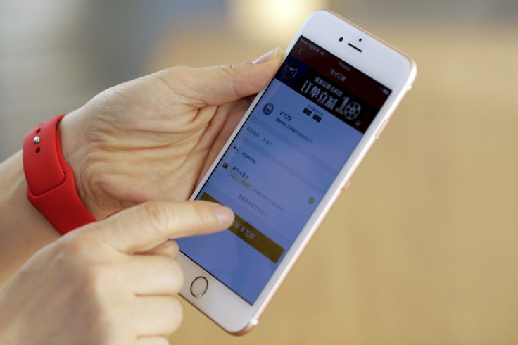 An employee uses an Apple iPhone to demonstrate to reporters how to pay using the Apple Pay service at an Apple store in Beijing, China, February 17, 2016.  