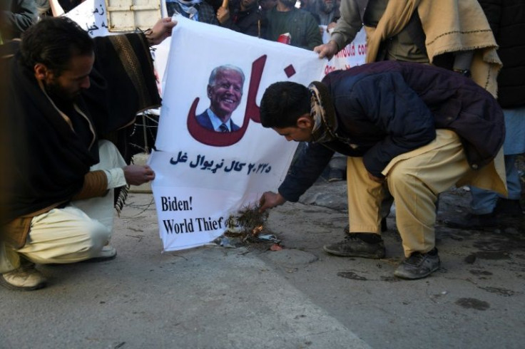Protesters burn a placard picturing Joe Biden