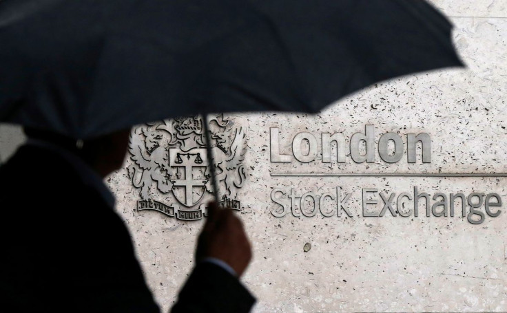A man shelters under an umbrella as he walks past the London Stock Exchange in London, Britain, August 24, 2015.