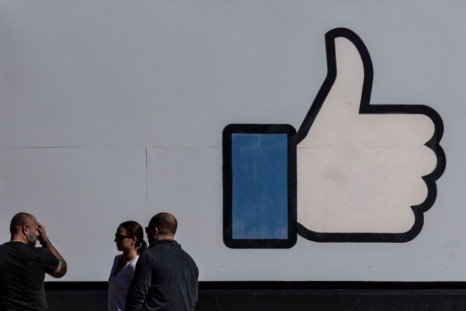 People stand in front of the entrance sign to Facebook headquarters in Menlo Park, California, U.S. October 27, 2021.  