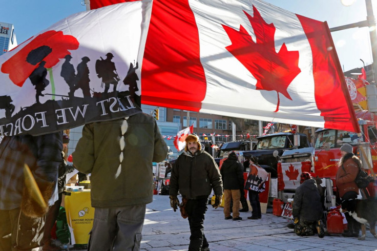 People stand with flags around parked trucks as protests against coronavirus disease (COVID-19) vaccine mandates continue, in Ottawa, Ontario, Canada, February 14, 2022.
