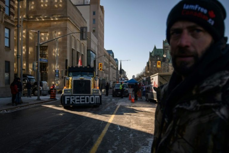 A demonstrator watches as a driver relocates his vehicle during a protest by truck drivers over pandemic health rules outside the parliament of Canada in Ottawa on February 14, 2022