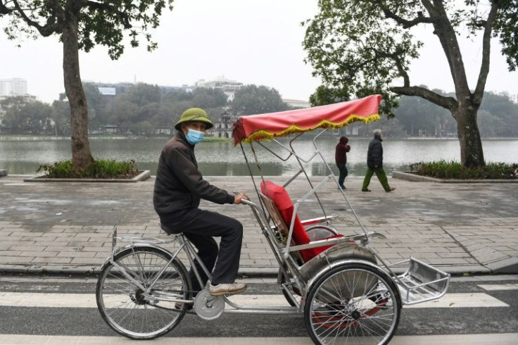 A bicycle taxi driver looks for customers by Hoan Kiem Lake in Hanoi