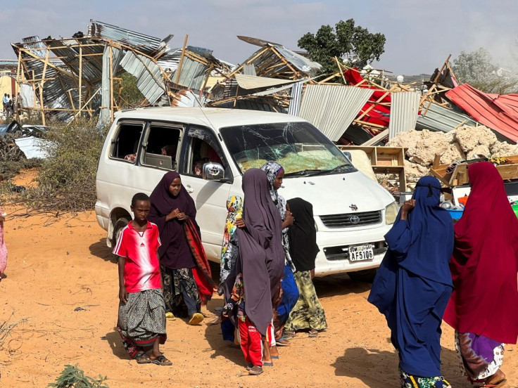 Somali women and children stand next a car and their destroyed homes following an overnight attack in Mogadishu, Somalia February 16, 2022.