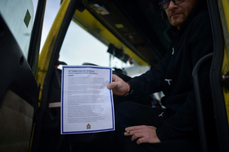 A protester poses with a police notice warning they face arrest if they don't leave, being handed out by authorities as the protest against Covid-19 health rules stretches into a third week