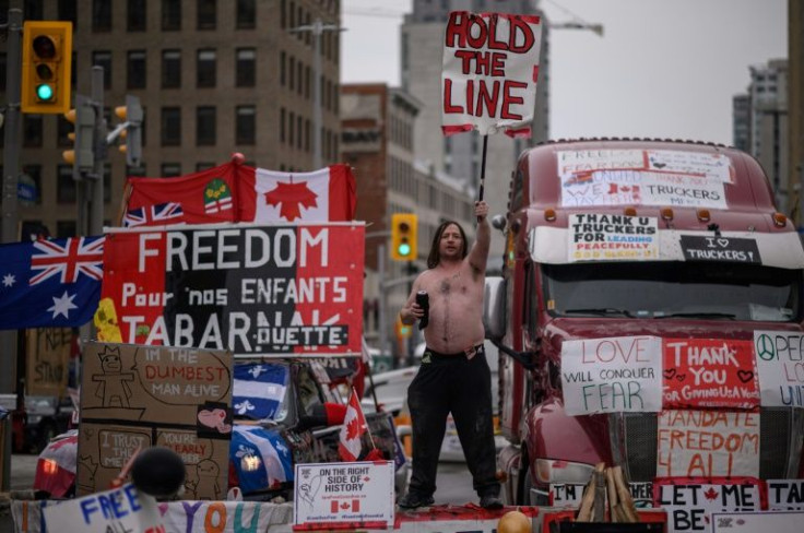 A demonstrator holds a placard during a protest by truck drivers over pandemic health rules and the Trudeau government, outside the parliament of Canada in Ottawa