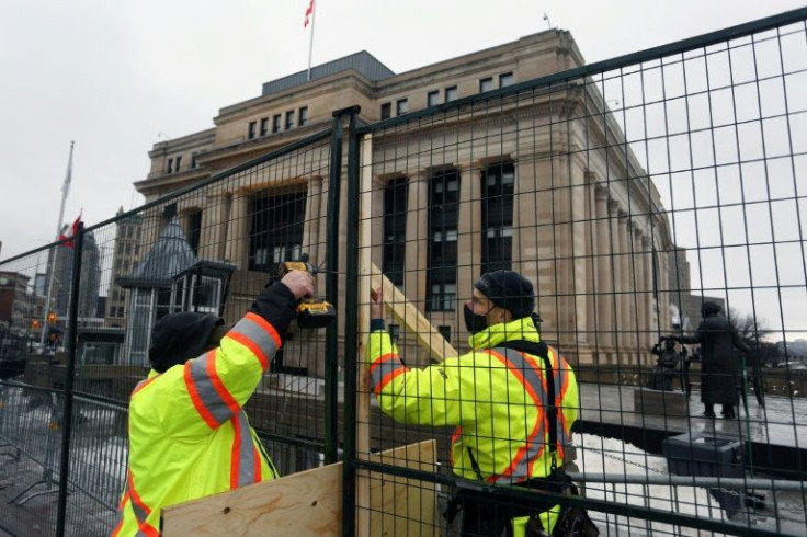 Workmen secure a fence around Canada's Senate as police readied to clear a trucker-led protest that has choked Ottawa's streets and provoked the government to call on rarely used emergency powers