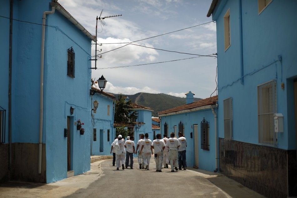 Painters walk along a street in Juzcar