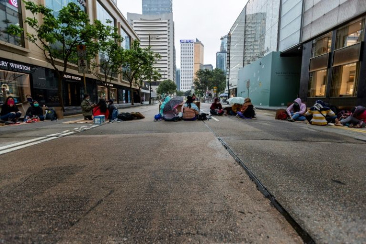 Domestic helpers wearing facemasks gather on a Hong Kong street on their one day off a week