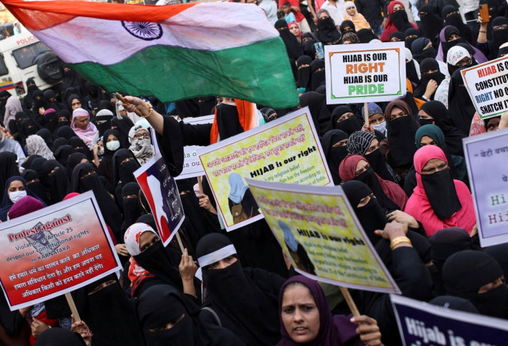A woman waves the Indian flag as others hold placards during a protest against the recent hijab ban in schools in Karnataka state, on the outskirts of Mumbai, India, February 13, 2022.