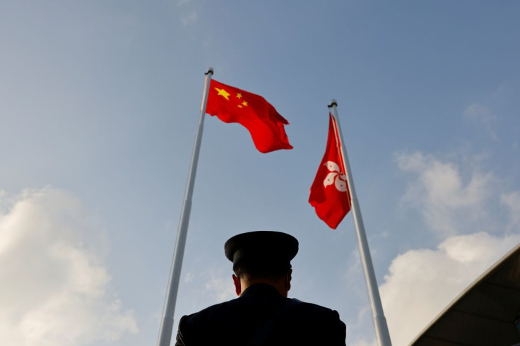 A police officer stands guard below China and Hong Kong flags during a flag raising ceremony, a week ahead of the Legislative Council election in Hong Kong, China, December 12, 2021. 
