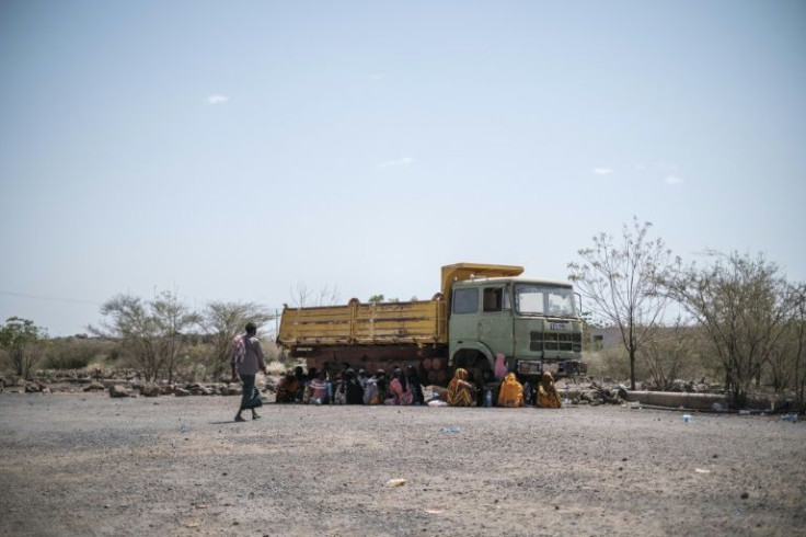 People sit in the shade of an abandoned truck in the compound of a hotel in the Afar capital Semera