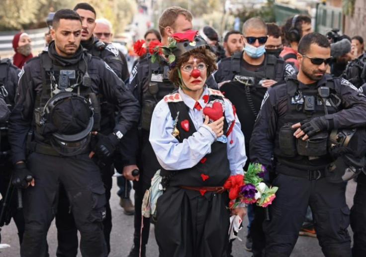 A protester dressed as a clown stands before Israeli police during a demonstration in the flashpoint neighbourhood of Sheikh Jarrah in Israeli-annexed east Jerusalem on February 18, 2022