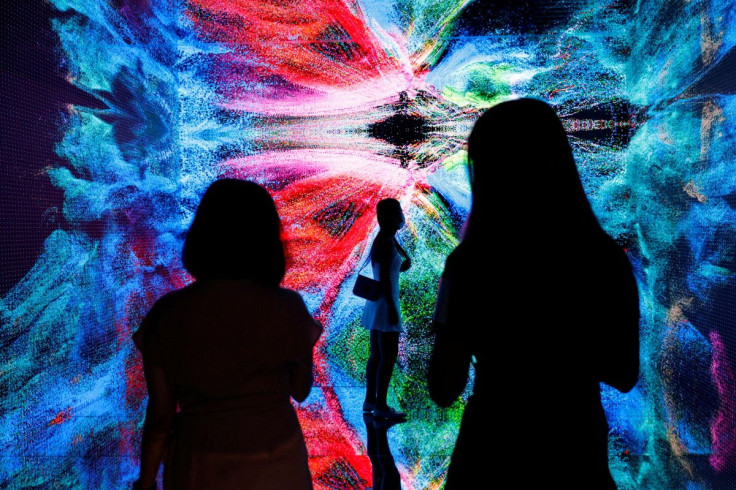 Visitors are pictured in front of an immersive art installation titled "Machine Hallucinations - Space: Metaverse" by media artist Refik Anadol at the Digital Art Fair, in Hong Kong, China September 30, 2021.
