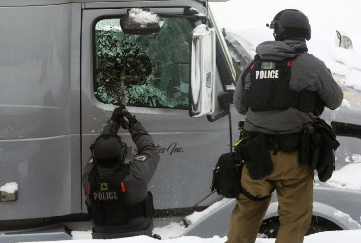 An officer smashes a truck window as police deploy to remove protesters on February 19, 2022 in Ottawa, Canada