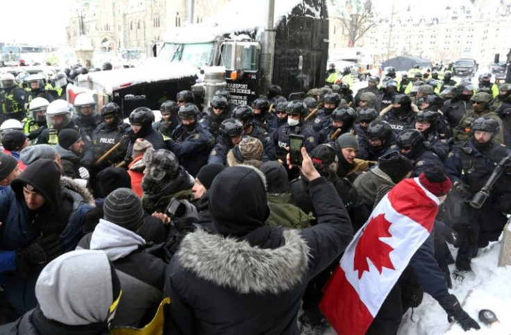 A line of police push protesters back on February 19, 2022 in Ottawa, Canada