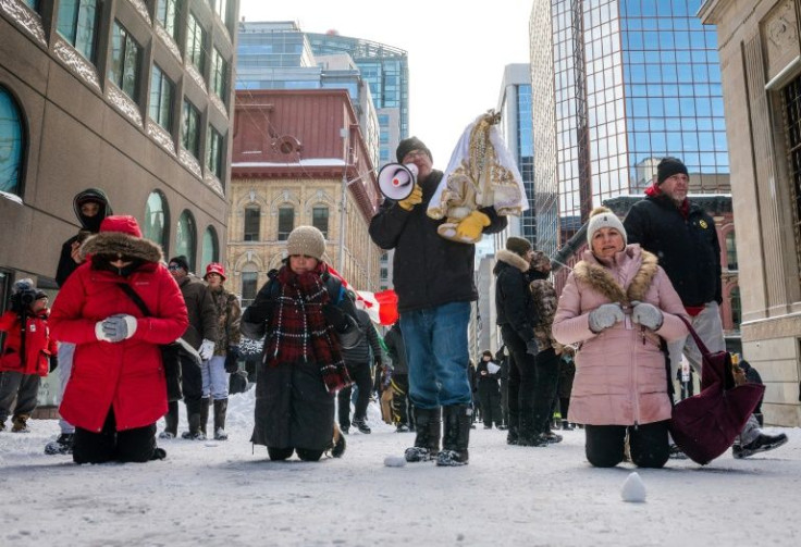 Demonstrators pray as as police deploy to remove them on February 19, 2022, in Ottawa, Canada