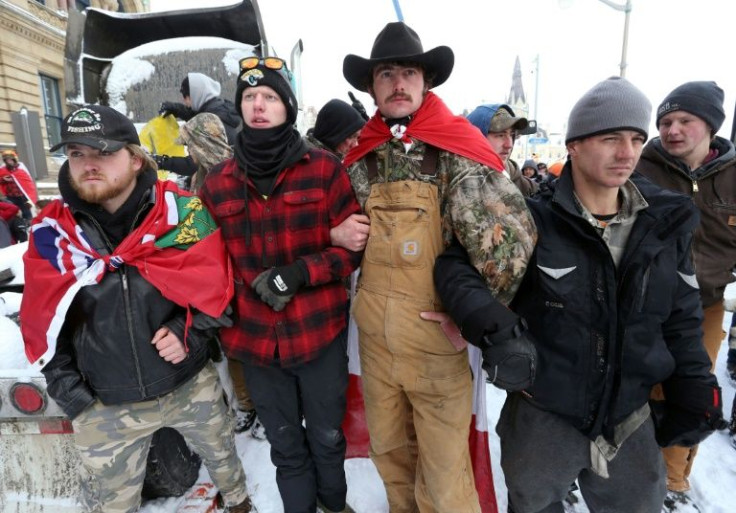 Protesters lock arms as a police line pushes forward on February 19, 2022 in Ottawa, Canada
