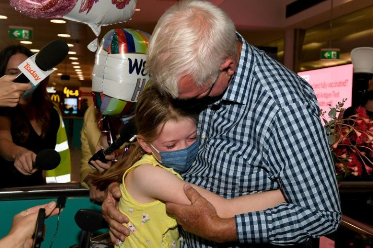 A man hugs his granddaughter upon arriving at Sydney International Airport as Australia reopens its borders for fully vaccinated visa holders, tourists and business travellers