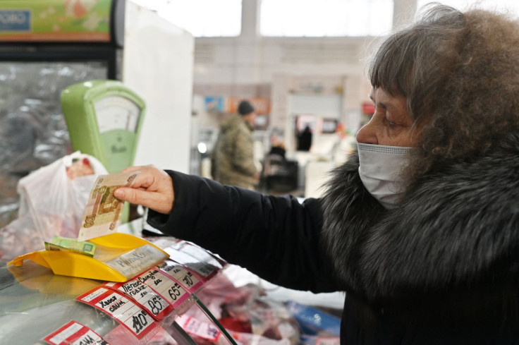 FILE PHOTO - A customer hands over Russian rouble banknotes to a vendor at a market in Omsk, Russia February 18, 2022.