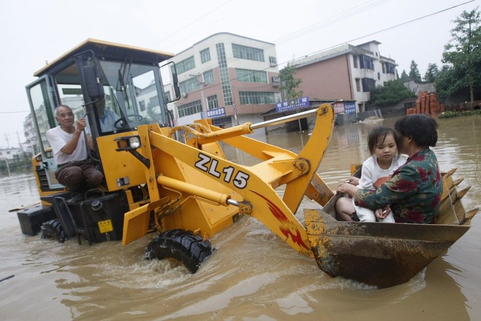 A rescuer transfer an elderly woman and her granddaughter with an excavator on a flooded street in Xianning