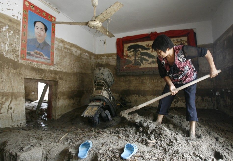 A woman shovels mud at her house after a landslide triggered by heavy rainfalls in Linxiang