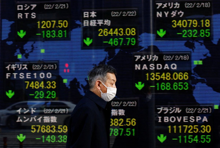 A man wearing a protective mask, amid the coronavirus disease (COVID-19) outbreak, walks past an electronic board displaying Japan's Nikkei index and various countries' stock market index prices outside a brokerage in Tokyo, Japan, February 22, 2022.