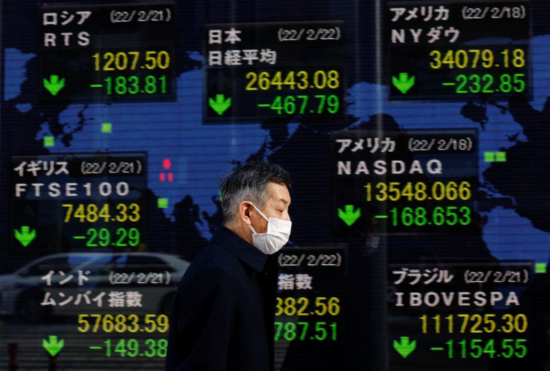 A man wearing a protective mask, amid the coronavirus disease (COVID-19) outbreak, walks past an electronic board displaying Japan's Nikkei index and various countries' stock market index prices outside a brokerage in Tokyo, Japan, February 22, 2022. 