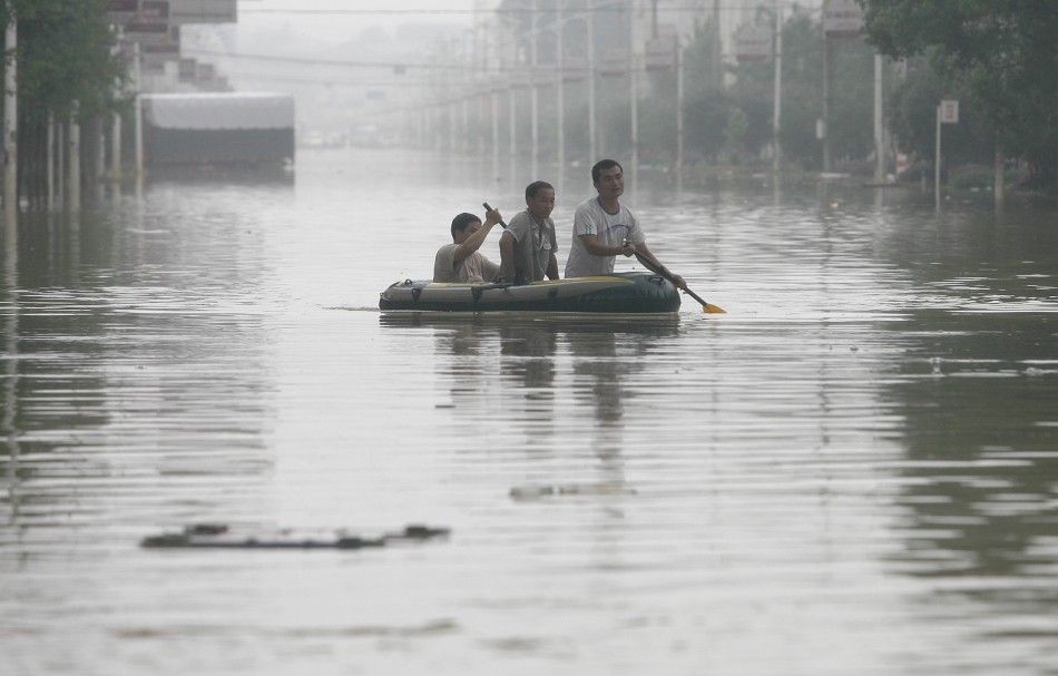 Residents row their rubber dinghy past a flooded street in Xianning