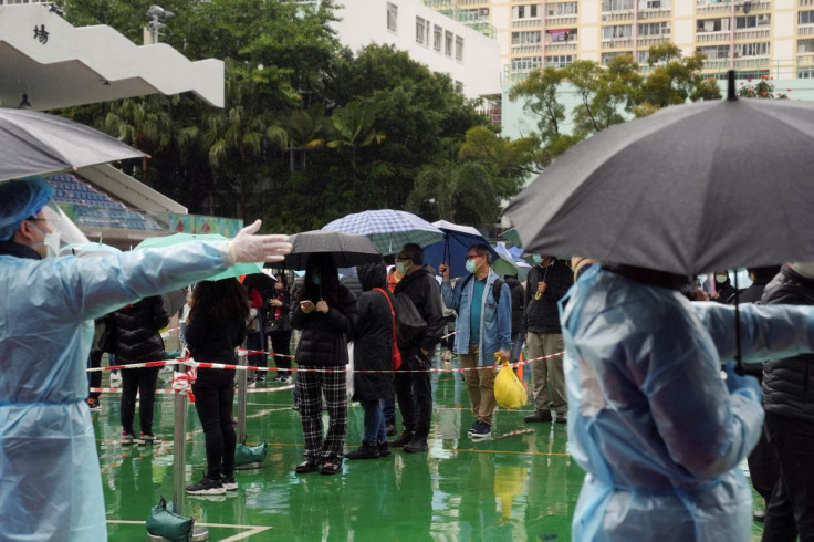 People holding umbrellas line up in the rain at a testing site for the coronavirus disease (COVID-19) in Hong Kong, China February 22, 2022.