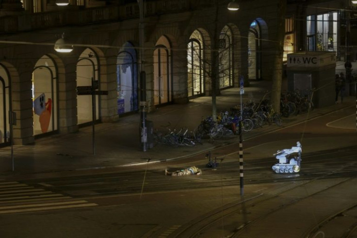 A man in camouflage clothing lies next to a police robot in a street after the hostage-taking ended in Amsterdam