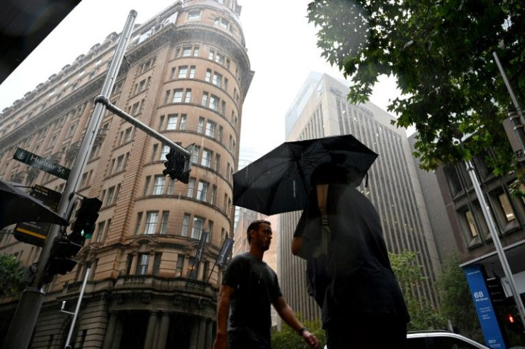 Pedestrians walk in heavy rain in the central business district of Sydney on February 22, 2022.