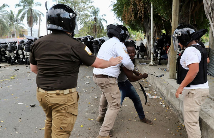 An agent of the National Migration Institute (INM) contains a migrant during a protest to demand speedy processing of humanitarian visas to continue on their way to the United States, outside the office of the National Migration Institute (INM) in Tapachu