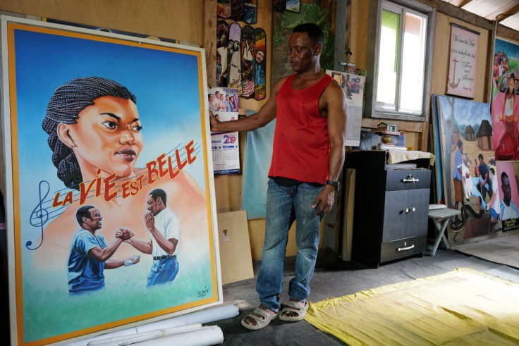 Ghanaian movie poster artist, Daniel Anum Jasper, 54, stands next to a hand-painted poster commissioned for a foreign client at his workshop in the Teshie area of Accra, Ghana February 11, 2022. Picture taken February 11, 2022.