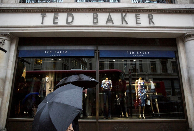 People shelter under umbrellas as they pass a Ted Baker a store in London, Britain October 06, 2015.