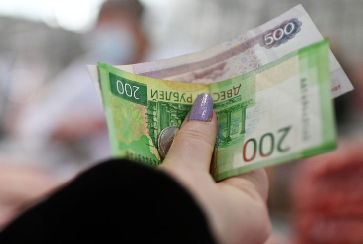 A customer hands over Russian rouble banknotes and coins to a vendor at a market in Omsk, Russia February 18, 2022. 