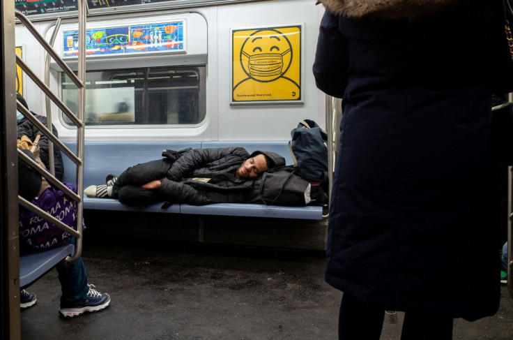 A homeless person sleeps on the subway during rush hour in New York City, U.S., February 21, 2022.  